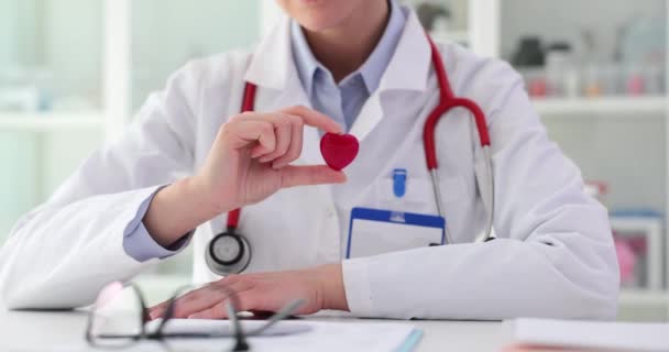 Kardiolog pokazuje czerwone małe serce. Koncepcja działalności charytatywnej w dziedzinie kardiologii miłość i medycyna - Materiał filmowy, wideo