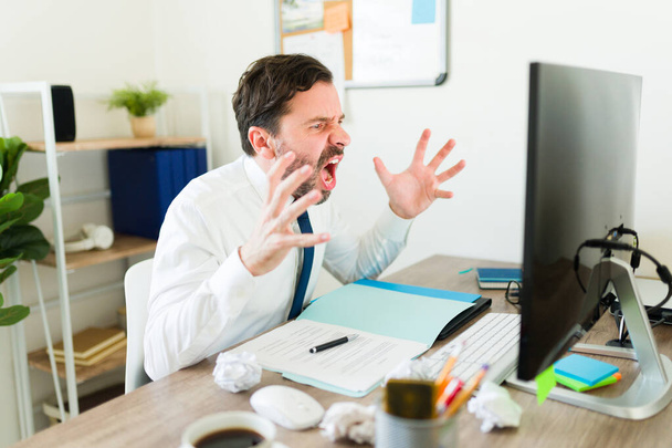 Arrabbiato imprenditore laywer o capo urlando mentre ha problemi di lavoro e guardando il suo schermo del computer urlando guardando sconvolto - Foto, immagini