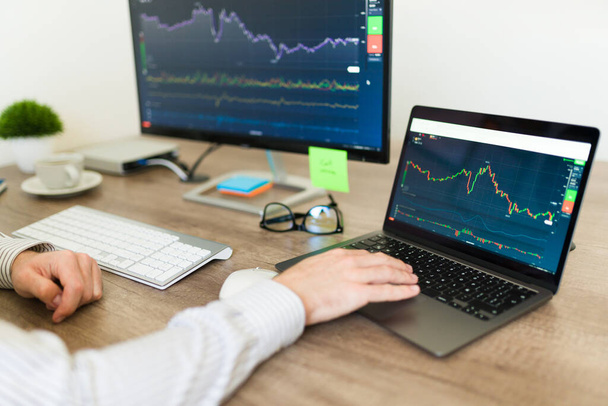 Broker o trader che lavorano su laptop e computer e controllano il mercato azionario mentre investono o acquistano azioni - Foto, immagini