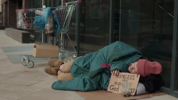 Lange kans om dakloos te slapen op karton, bedelend om geld naast het kantoor. - Video