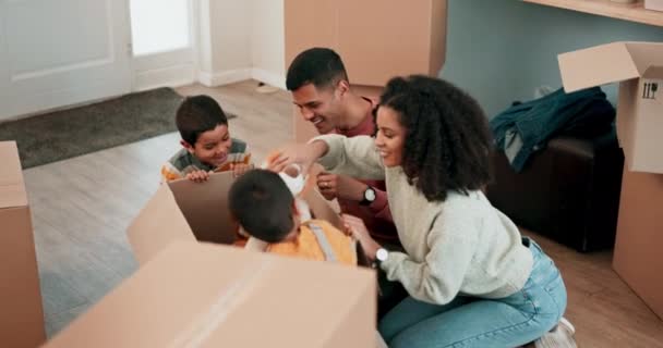 Μετακίνηση, παιχνίδια και την οικογένεια με χαρτονένια κουτιά στο νέο τους σπίτι συγκόλληση και να παίζουν μαζί. Ευτυχισμένοι, χαμογελαστοί και νέοι γονείς να παίζουν με αρκουδάκια με τα παιδιά τους σε ένα μοντέρνο σπίτι - Πλάνα, βίντεο