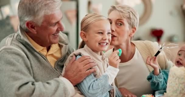 Grootouders, kinderen en verjaardagsfeest in het ouderlijk huis, samen en pratend met knuffel, kus en zorg. Senior man, vrouw en jonge kinderen met snoep, liefde en feest in huis met speelse lach. - Video