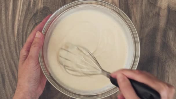 Bowl of white chocolate vanilla bean pudding on a wooden table. Mixing pudding mix and milk in a glass bowl - Footage, Video