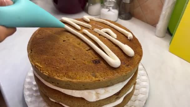 Ζαχαροπλάστης με λωρίδες κρέμας από μια σακούλα ζαχαροπλαστικής σε ένα κέικ. Υψηλής ποιότητας 4k πλάνα - Πλάνα, βίντεο