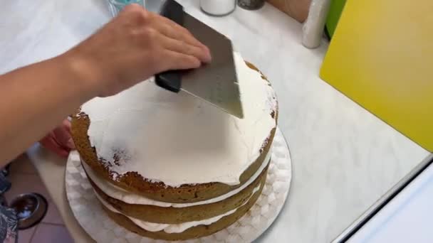 Cook levittää kermaa kakun pinnalle lastalla. Laadukas 4k kuvamateriaalia - Materiaali, video