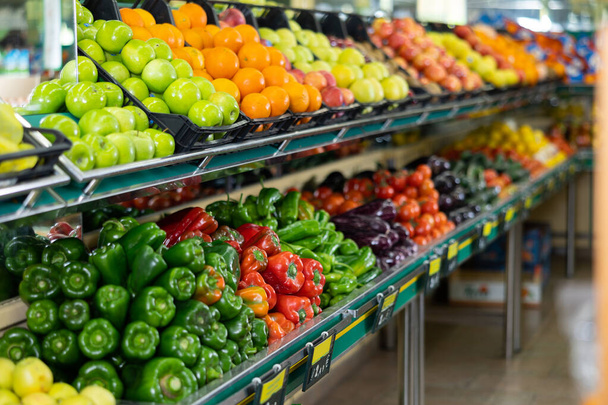 Stand of boxes full of fresh colorful fruits and vegetables in big grocery store - Photo, image