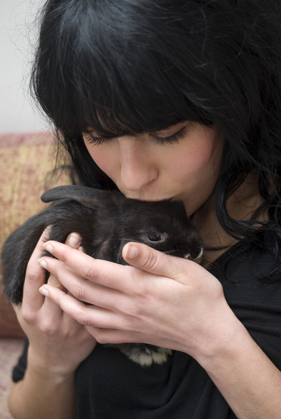 Young woman caressing her pet rabbit at home - Photo, Image