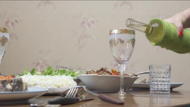 Vrouwenhand giet witte wijn in glas op de eettafel. - Video