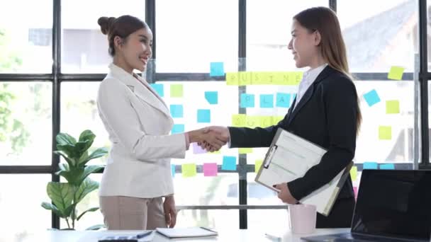Twee Aziatische zakenvrouwen schudden elkaar de hand voor een team van bedrijfsfusies en overnames, succesvolle onderhandelingen, handen schudden met partners die partnerschap vieren - Video