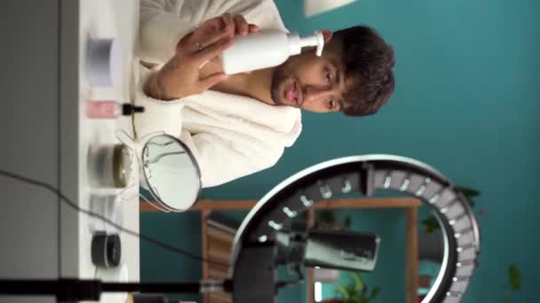 Muszlim férfi szépség blogger forgatás napi bőrápolási rutin bemutató kamera, reklám kozmetikai termékek online. Influencer élő reaming kozmetikai termék felülvizsgálat otthon. Függőleges videó - Felvétel, videó