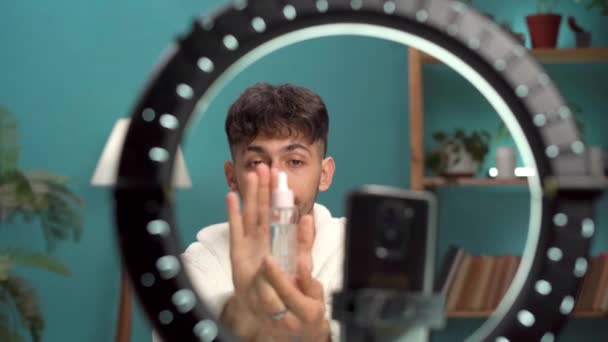 Arab szépség férfi blogger szérum forgatás napi bőrápolási rutin bemutató kamera. Befolyásoló srác élőben kozmetikai termék felülvizsgálat otthon belsejében. Férfi kozmetikai termék. Fénymásolási hely - Felvétel, videó
