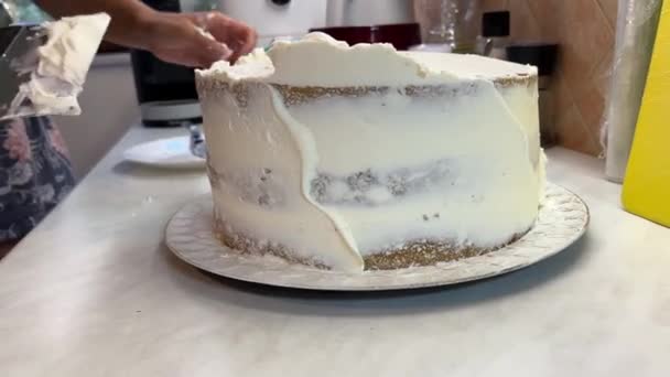 La donna stende uniformemente la crema sulla superficie della torta con una spatola. Filmati 4k di alta qualità - Filmati, video