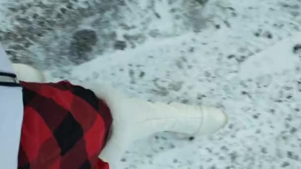 Tytöt jalat valkoisissa saappaissa kävelemässä lumessa. ihmisten jalat ovat lumessa jättäen jälkiä, menee pois. Laadukas 4k kuvamateriaalia. - Materiaali, video