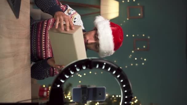 Hombre árabe blogger unboxing paquete con nuevos auriculares inalámbricos en la cámara en Navidad, la grabación de vídeo para su blog de tecnología en casa. Revisión del producto Tech. Copiar espacio - Metraje, vídeo