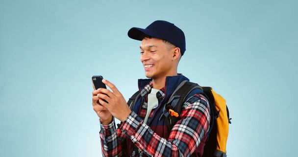 ハイキング,笑顔,タイピングは,青いスタジオの背景にソーシャルメディアで男性,携帯電話,冒険と. スマートフォン,モバイルユーザー,旅行やモックアップスペースとの接触を持つ人,ハイカー,モデル. - 写真・画像