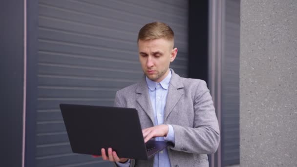 Ocupado hombre de negocios escribiendo en el ordenador portátil, mientras que agitando la mano a su colega al aire libre. Negocios, concepto tecnológico. Movimiento lento - Imágenes, Vídeo