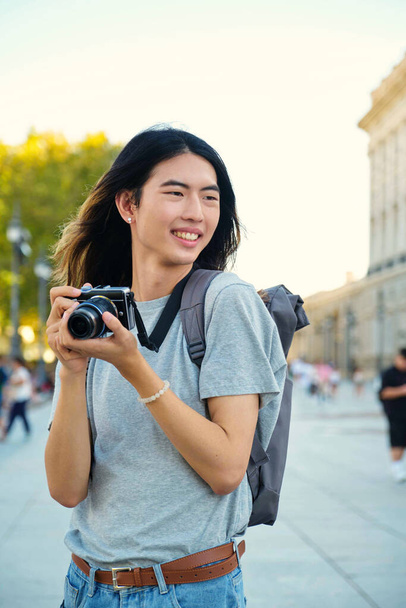Azjatycki turysta uśmiechnięty aparatem fotograficznym podczas zwiedzania Madrytu, Hiszpania. - Zdjęcie, obraz