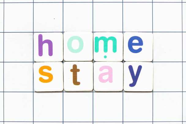 Kleurrijke tegel letter in woord home verblijf op witte raster achtergrond - Foto, afbeelding