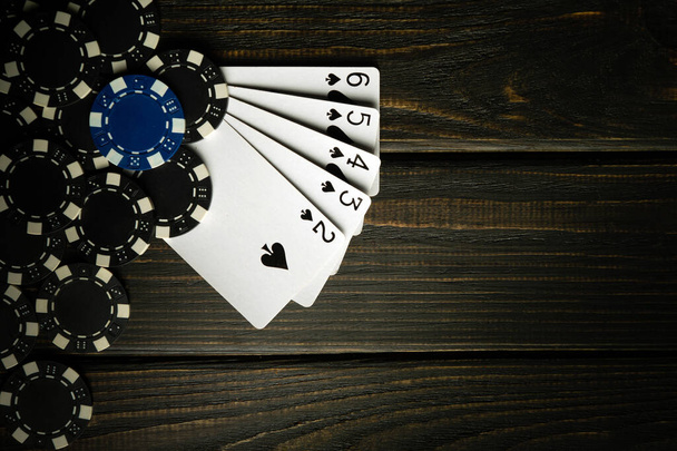 Populární a vzrušující pokerová hra s vítěznou přímou kombinací flush. Karty s žetony na tmavém vinobraní stolu v pokerovém klubu. - Fotografie, Obrázek