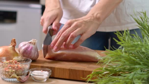 Una donna taglia un filetto di petto di pollo. Scatto ravvicinato in una bella cucina luminosa. Filmati 4k di alta qualità - Filmati, video