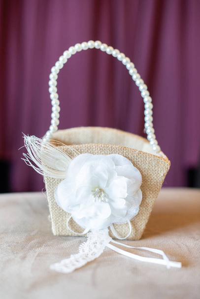 Wicker basket with pearl handle and white flower decoration purple background - Photo, Image