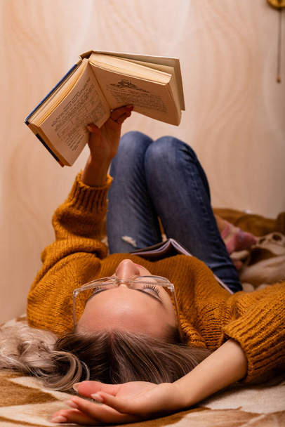 Γυναίκα με ένα βιβλίο στον καναπέ. Μια γυναίκα διαβάζει ένα βιβλίο. Μαθαίνω στο σπίτι. Υψηλής ποιότητας φωτογραφία - Φωτογραφία, εικόνα