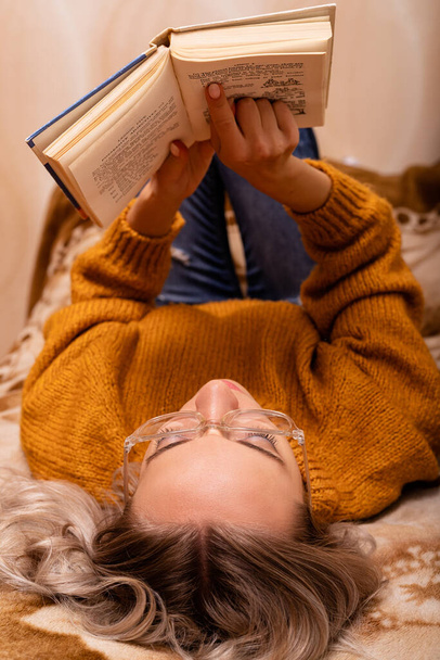 Mujer con un libro en el sofá. Una mujer lee un libro. Aprender en casa. Foto de alta calidad - Foto, Imagen
