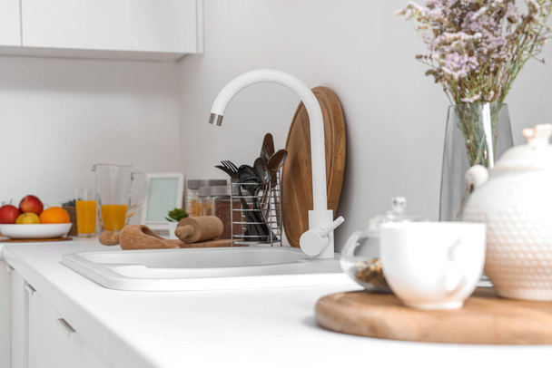 White counters with sink and utensils in interior of modern kitchen, closeup - Photo, Image