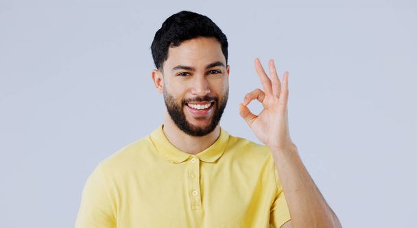 Ok, hands and portrait of man in studio for vote, certified review or feedback on white background. Happy indian model show emoji for success, agreement and icon of support, yes or sign of excellence. - Foto, Imagen