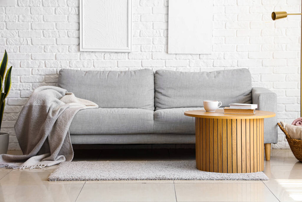Interno di luminoso soggiorno con plaid su divano grigio - Foto, immagini