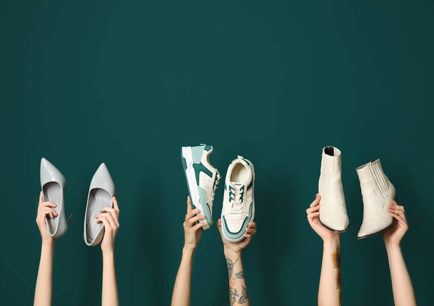 Ženy drží různé stylové boty na zeleném pozadí - Fotografie, Obrázek