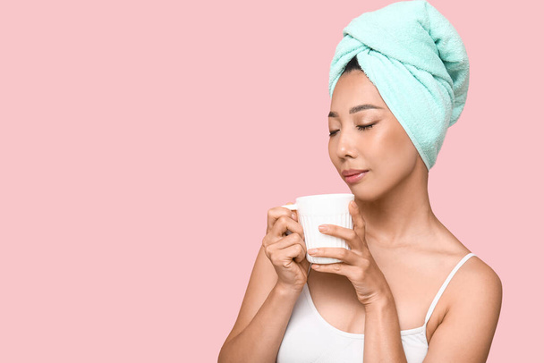 Joven mujer asiática después de la ducha con taza de café sobre fondo rosa, primer plano - Foto, imagen