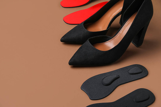 Pair of stylish high heeled shoes and orthopedic insoles on color background - Photo, Image