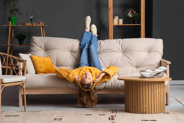 Junge Frau mit Kopfhörer entspannt auf Sofa zu Hause - Foto, Bild