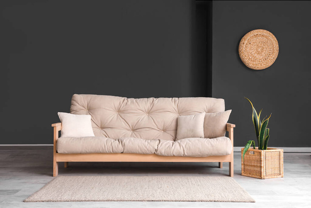 Інтер'єр стильної вітальні з диваном і рослиною - Фото, зображення