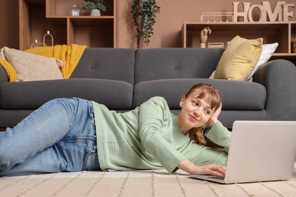 Молода жінка використовує ноутбук на підлозі вдома - Фото, зображення