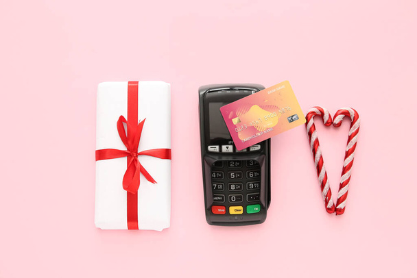 Terminale di pagamento con carta di credito, confezione regalo di Natale e bastoncini di zucchero su sfondo rosa - Foto, immagini