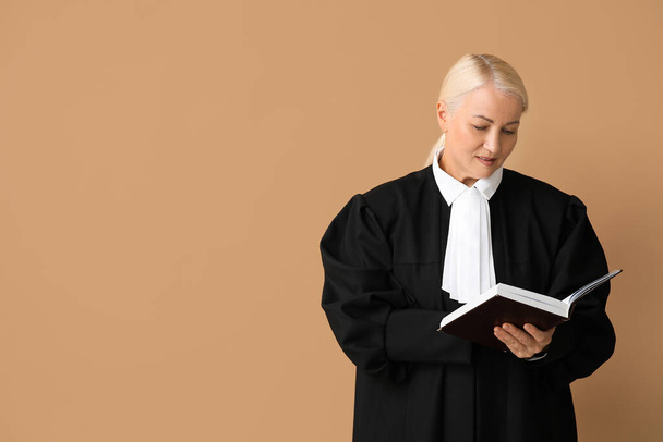 Mature female judge with book on brown background - Photo, Image