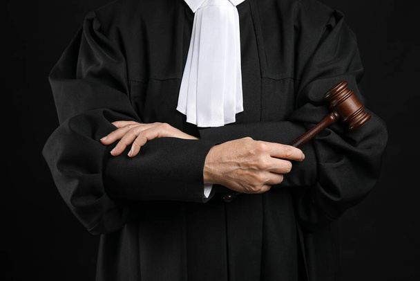 Kobieta sędzia z skrzyżowanymi ramionami i młotkiem na czarnym tle - Zdjęcie, obraz