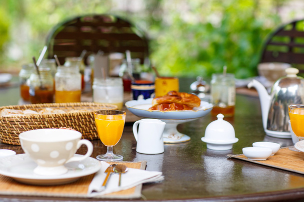 Стол накрыт на завтрак с различными вареньем кофе, круа
 - Фото, изображение