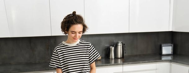 tiro vertical de jovem mulher sorridente cozinhar na cozinha, cortar legumes no balcão, fazer refeição saudável, comida vegetariana. - Foto, Imagem