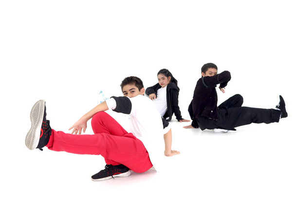 Happy student kid group studying modern style dance in indoor studio classroom, children, boys and girl, dancing on white background. Three little dancers practicing break dance together. - Photo, Image