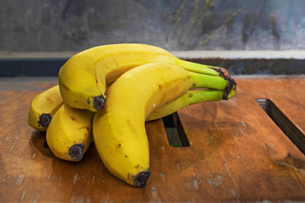 Bund reife gelbe Banane auf einer Holzoberfläche. - Foto, Bild