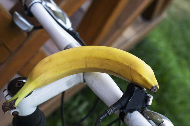 спелый желтый банан на руле велосипеда. Тренировки и правильное питание - Фото, изображение