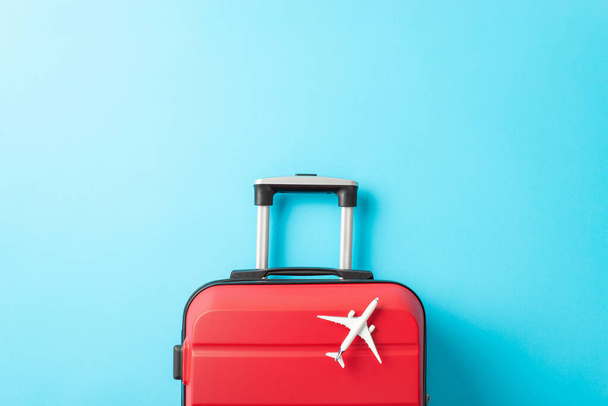 Air Travel uudenvuoden: Overhead tilannekuva esittelee punainen matkalaukku, ja pieni lentokone malli eloisa sininen kangas tyhjä tila tervehdys viesti tai edistäminen - Valokuva, kuva