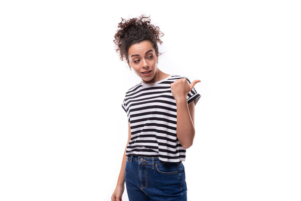 nuori valkoihoinen nainen kihara musta tukka pukeutunut raidallinen t-paita osoittaa kätensä sivulle. - Valokuva, kuva