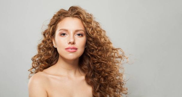 Cheerful woman with wavy hair and natural makeup. Young fashion model with long curly hairstyle and fresh clear skin posing on white background - Photo, Image