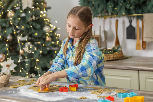 Child girl prepare ginger cookies for Christmas holiday and play with cookie cutters. Christmas time. - Photo, Image