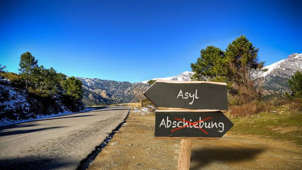 An image with a signpost pointing in two different directions in German. One direction points to asylum, the other points to deportation. - Photo, Image