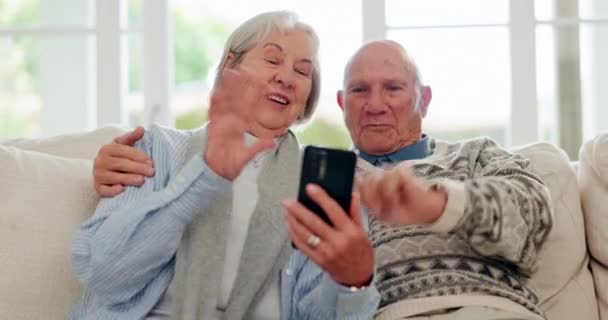 Old couple, video call and talking on sofa wave for online communication, social media or happy connection. Senior partnership, smile and mobile for chat discussion or web network, scroll or hello. - Footage, Video